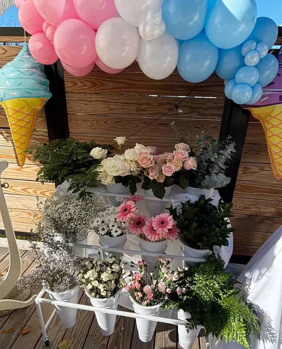 Chariot à fleurs à trois étages avec seaux blancs de roses, gerberas roses, gypsophile, marguerites, eucalyptus et fougères