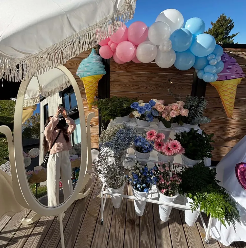 Invitée qui se photographie dans le miroir ovale à côté du bar à fleurs et des roses bleues