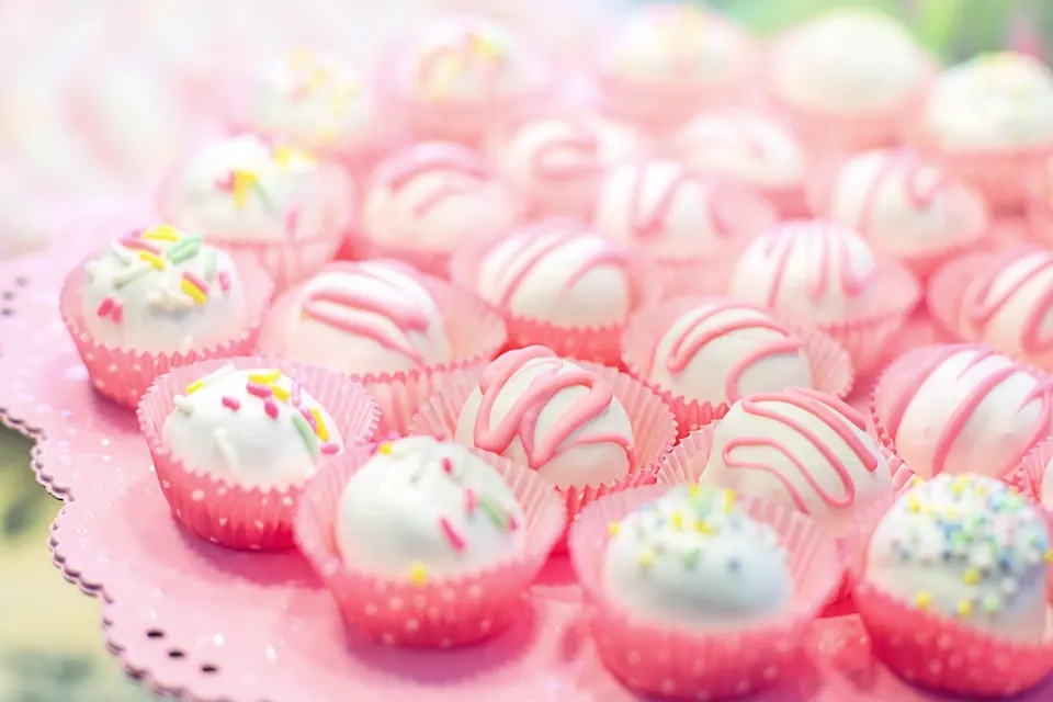 Bouchées de gâteau enrobées de chocolat blanc et de rose dans des caissettes roses