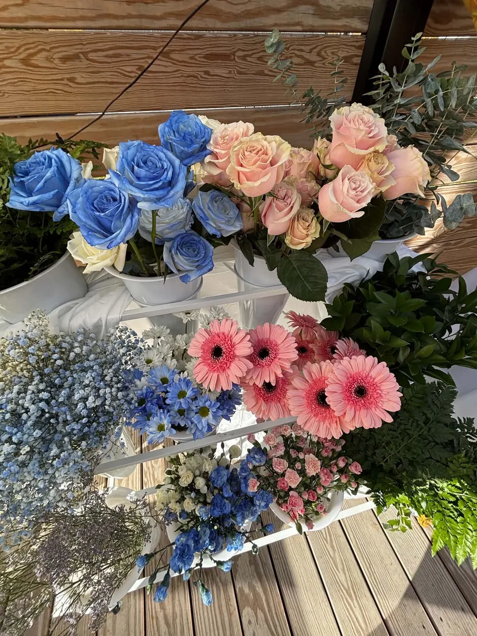 Gros plan de roses bleues, roses pêche, gerberas roses, gypsophile bleu, marguerites et œillets miniatures