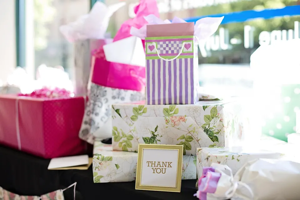 Table de cadeaux emballés en rose et à motifs floraux avec une carte Thank you