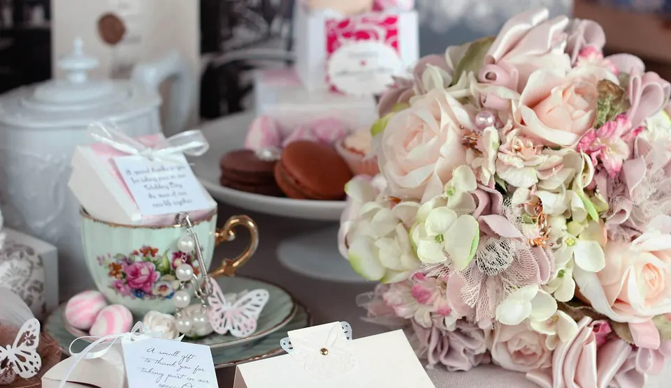 Table de shower de mariée avec tasses de thé en porcelaine, macarons, petites boîtes cadeaux et bouquet de roses pâles
